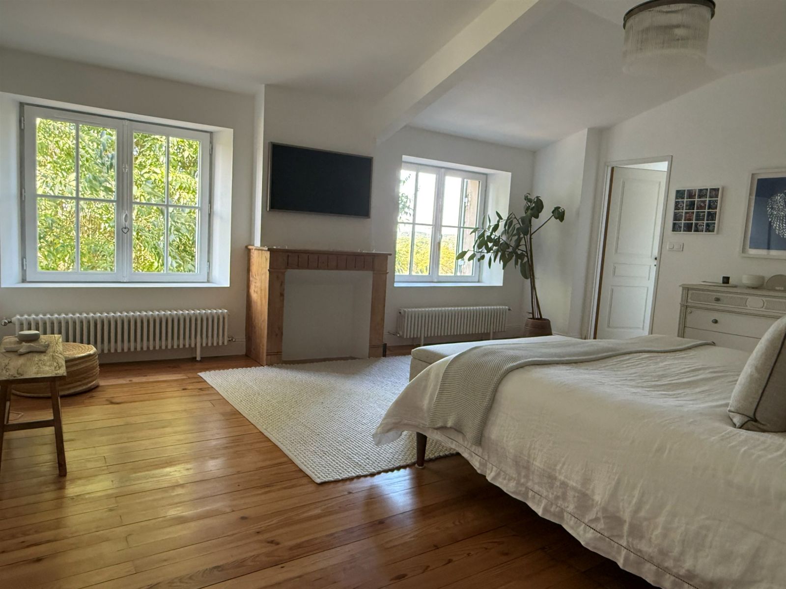 Master bedroom with a pale upholstered bed and tall windows