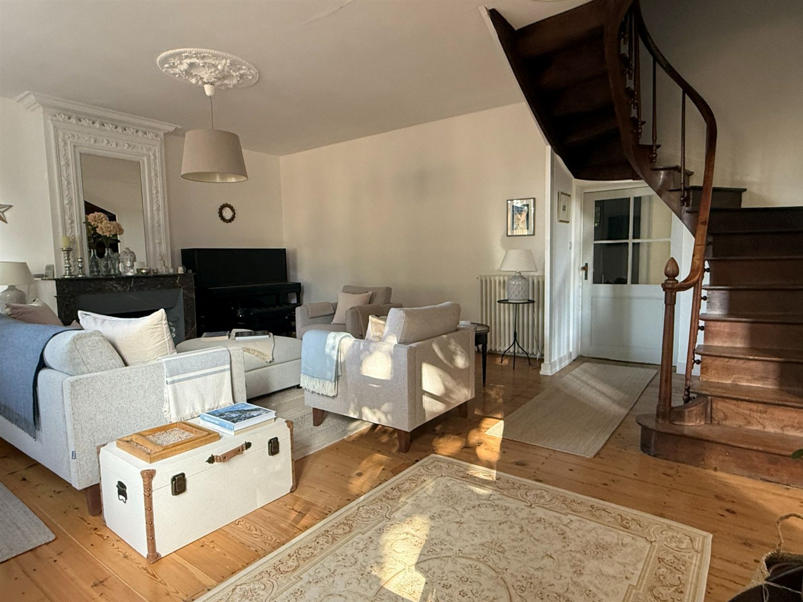 Entrance lounge with pale sofas, fireplace and staircase