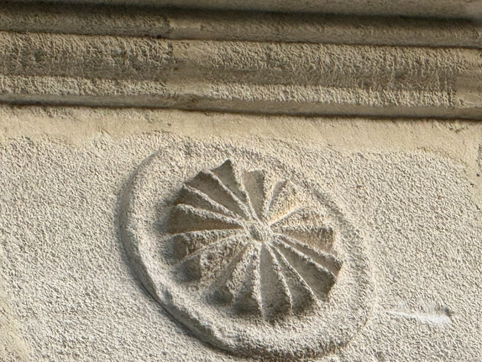 Circular carved stone motif beneath horizontal stone mouldings